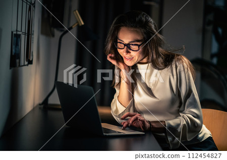 Woman using laptop for remote working at home at night in dark room 112454827
