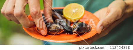 Heap of mussels in shells stuffed with rice. Man is going to eat midye traditional Turkish food. Istanbul, Turkey BANNER, LONG FORMAT Heap of mussels in shells stuffed with rice. Man is going to eat midye traditional Turkish food. Istanbul, Turkey BANNER, LONG FORMAT 112454828