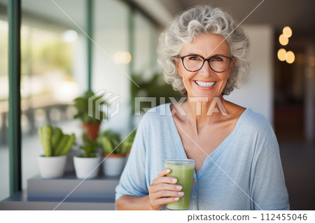 smiling senior woman with green smoothie in glass at home kitchen 112455046
