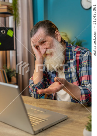 Displeased sad senior man using laptop receive bad news loss game fail computer virus at home office Displeased sad senior man using laptop receive bad news loss game fail computer virus at home office 112455061