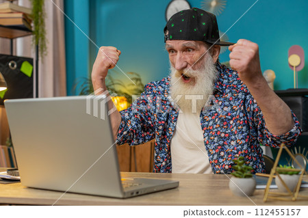 Happy senior man grandfather celebrate success win money in lottery on laptop get online good news 112455157