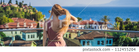 Woman tourist in Old town Kaleici in Antalya. Turkiye. Panoramic view of Antalya Old Town port, Taurus mountains and Mediterrranean Sea, Turkey BANNER, LONG FORMAT 112455204