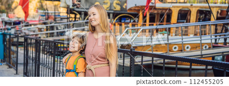 BANNER, LONG FORMAT Mom and son tourists in Old town Kaleici in Antalya. Turkiye. Panoramic view of Antalya Old Town port, Taurus mountains and Mediterrranean Sea, Turkey. Traveling with kids concept BANNER, LONG FORMAT Mom and son tourists in Old town Kaleici in Antalya. Turkiye. Panoramic view of Antalya Old Town port, Taurus mountains and Mediterrranean Sea, Turkey. Traveling with kids concept 112455205