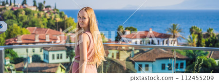 Woman tourist in Old town Kaleici in Antalya. Turkiye. Panoramic view of Antalya Old Town port, Taurus mountains and Mediterrranean Sea, Turkey BANNER, LONG FORMAT 112455209
