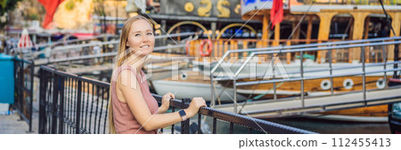 Woman tourist in Old town Kaleici in Antalya. Turkiye. Panoramic view of Antalya Old Town port, Taurus mountains and Mediterrranean Sea, Turkey BANNER, LONG FORMAT 112455413