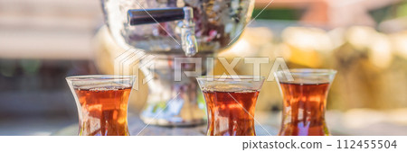 Drinking Traditional Turkish Tea with Turkish tea cup and copper tea pot BANNER, LONG FORMAT 112455504