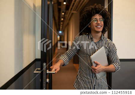 Man in striped shirt with laptop in hands opening door in the hotel Man in striped shirt with laptop in hands opening door in the hotel 112455918