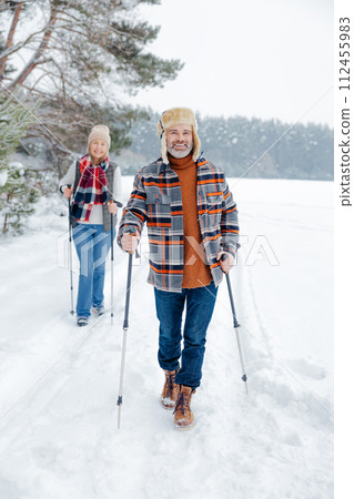 Man and woman looking enjoyed and contented while walking with sticks Man and woman looking enjoyed and contented while walking with sticks 112455983