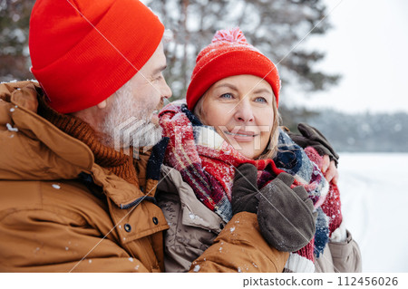 Mature couple looking close and romantic while spending time in a winter park 112456026