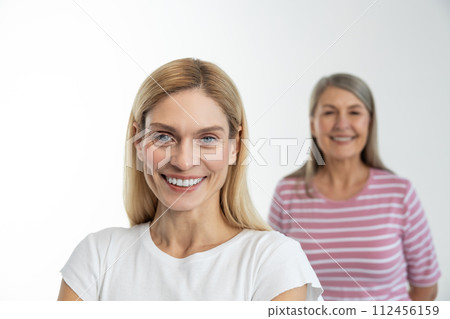 Blonde cute woman smiling nicely, her mom standing behind 112456159