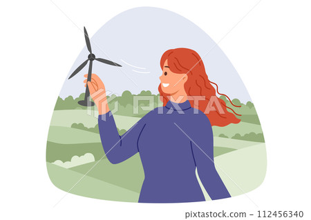 Wind turbine in hands of woman with smile standing in nature, and developing alternative energy 112456340