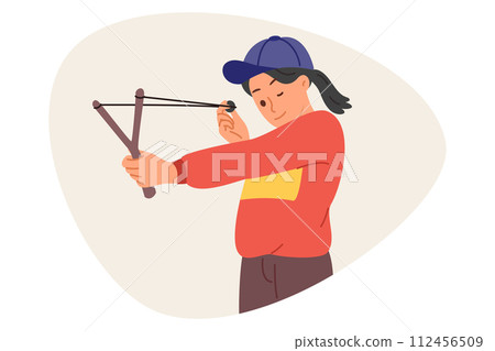 Little mischievous girl shoots with slingshot, closing one eye to aim at target during weekend Little mischievous girl shoots with slingshot, closing one eye to aim at target during weekend 112456509