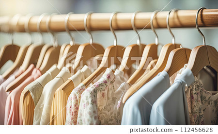 wooden hangers with dresses in light summer colors, hanging in a row 112456628