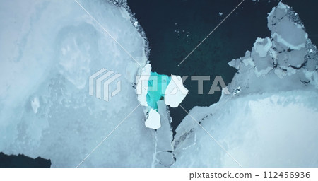 Crashed ice glacier in Antarctica aerial top view. Huge iceberg with melting blue water hole inside, polar nature environment. Arctic winter landscape at global warming problem. Crashed ice glacier in Antarctica aerial top view. Huge iceberg with melting blue water hole inside, polar nature environment. Arctic winter landscape at global warming problem. 112456936