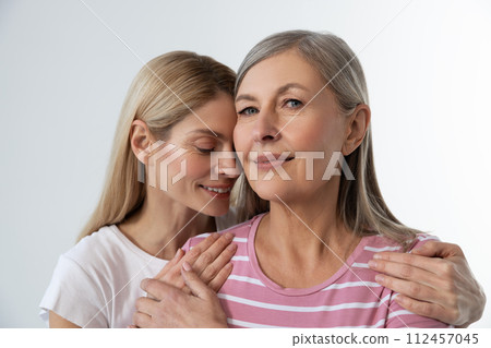 Blonde young woman embracing her mom and smiling tenderly 112457045