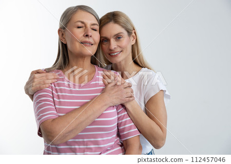Blonde young woman embracing her mom and smiling tenderly 112457046