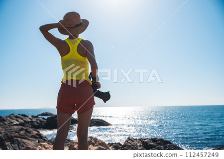 Woman taking photo on sunrise seaside rocky mountains 112457249