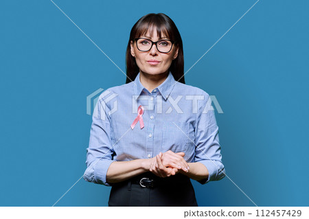 Middle-aged woman with pink ribbon symbolizing International Breast Cancer Day 112457429
