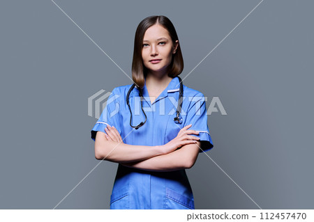 Portrait of young female nurse looking at camera on gray background 112457470