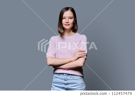 Young confident woman with crossed arms on gray background 112457479