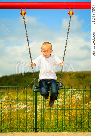 Little blonde boy child having fun on a swing outdoor Little blonde boy child having fun on a swing outdoor 112457807