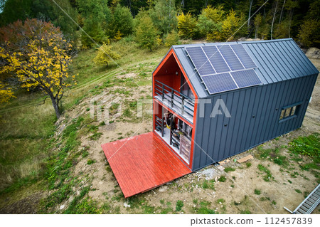 New modern house cottage with solar photovoltaic panel system on roof. Aerial view. Concept of alternative, renewable energy and home autonomy. 112457839