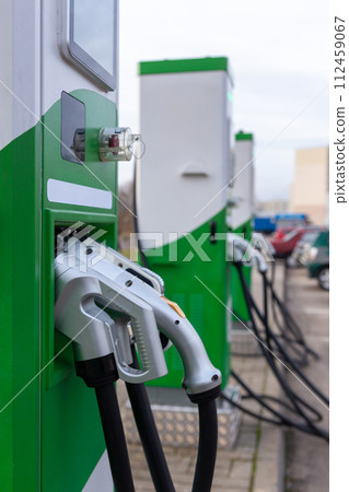 Car parking with charging stations near a multi-storey apartment building. 112459067