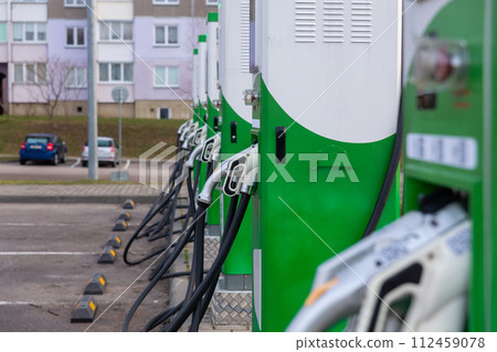 Car parking with charging stations near a multi-storey apartment building. 112459078