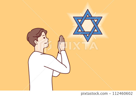 Jewish man teenager prays, looking at star of David, observing ritual in preparation for shabbat 112460602