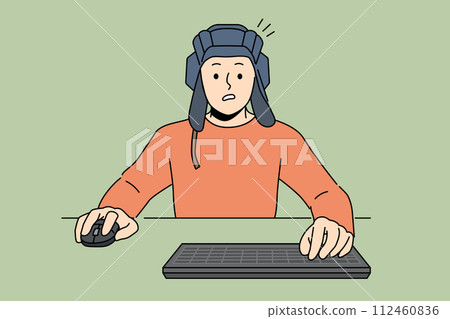 Man gamer plays tanks on computer, sitting at table with keyboard and wears tanker helmet 112460836