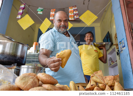 Seller offering Traditional Namkeen snack and Samosas on street food and markets 112461185