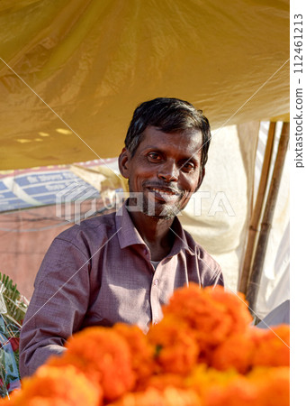 Florist seller at flower market smiling with orange flowers in India 112461213