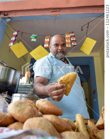 Seller offering Traditional Namkeen snack and Samosas on street food and markets Seller offering Traditional Namkeen snack and Samosas on street food and markets 112461223
