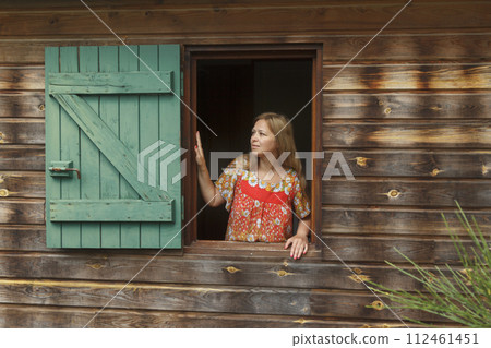 Woman in window of wooden house Woman in window of wooden house 112461451