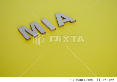 MIA wooden letters representing Missing In Action on yellow background 112462566