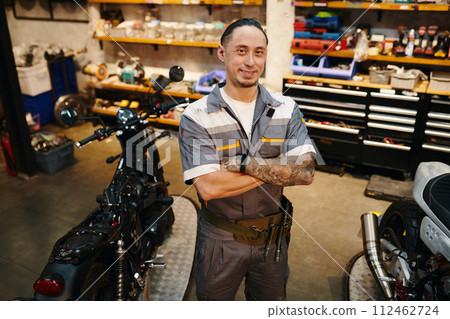 Portrait of smiling repairman working in motorcycle garage 112462724