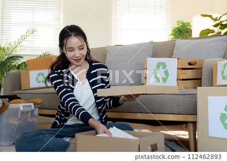 Woman pack box with used clothes for reuse. Reusing, recycling material and reducing waste in fashion, second hand apparel idea. Circular fashion, zero waste concept Woman pack box with used clothes for reuse. Reusing, recycling material and reducing waste in fashion, second hand apparel idea. Circular fashion, zero waste concept 112462893