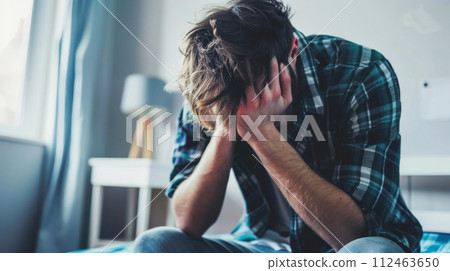 AI-generated content. Despairing Young Man Overwhelmed with Emotions at Home. Distressed individual facing tough times, seeking solace in solitude. 112463650