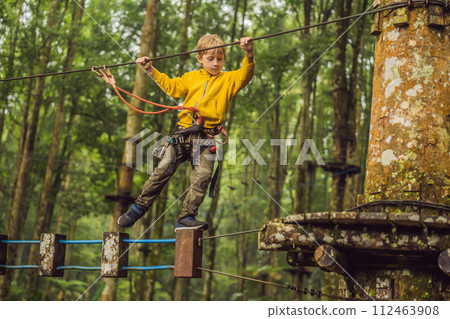 Little boy in a rope park. Active physical recreation of the child in the fresh air in the park. Training for children Little boy in a rope park. Active physical recreation of the child in the fresh air in the park. Training for children 112463908