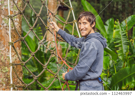 strong young men in a rope park on the wood background strong young men in a rope park on the wood background 112463997
