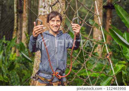 strong young men in a rope park on the wood background strong young men in a rope park on the wood background 112463998