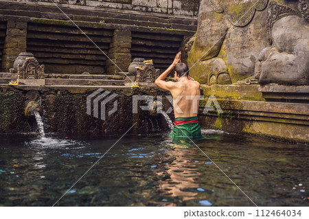 Man in holy spring water temple in bali. The temple compound consists of a petirtaan or bathing structure, famous for its holy spring water 112464034