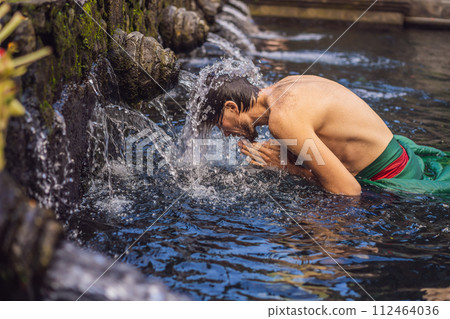 Man in holy spring water temple in bali. The temple compound consists of a petirtaan or bathing structure, famous for its holy spring water Man in holy spring water temple in bali. The temple compound consists of a petirtaan or bathing structure, famous for its holy spring water 112464036