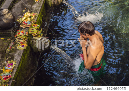 Man in holy spring water temple in bali. The temple compound consists of a petirtaan or bathing structure, famous for its holy spring water Man in holy spring water temple in bali. The temple compound consists of a petirtaan or bathing structure, famous for its holy spring water 112464055