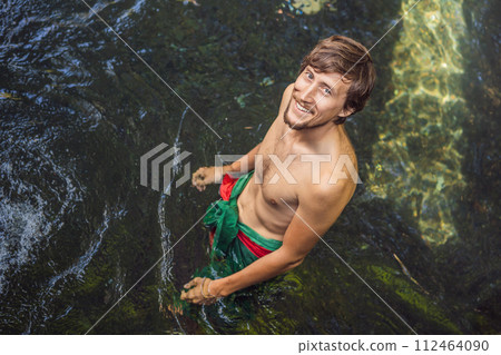 Man in holy spring water temple in bali. The temple compound consists of a petirtaan or bathing structure, famous for its holy spring water Man in holy spring water temple in bali. The temple compound consists of a petirtaan or bathing structure, famous for its holy spring water 112464090