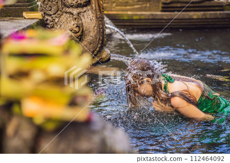 Woman in holy spring water temple in bali. The temple compound consists of a petirtaan or bathing structure, famous for its holy spring water Woman in holy spring water temple in bali. The temple compound consists of a petirtaan or bathing structure, famous for its holy spring water 112464092