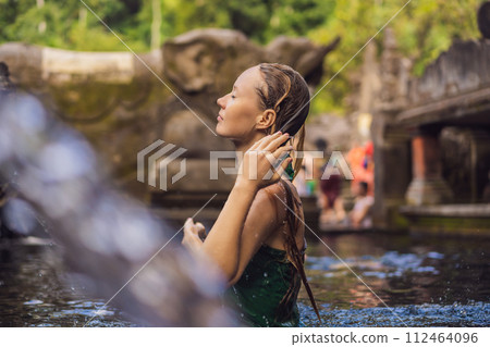 Woman in holy spring water temple in bali. The temple compound consists of a petirtaan or bathing structure, famous for its holy spring water Woman in holy spring water temple in bali. The temple compound consists of a petirtaan or bathing structure, famous for its holy spring water 112464096
