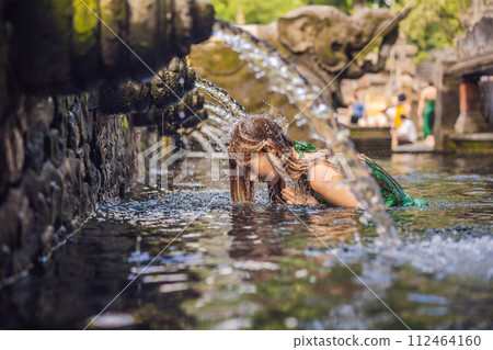 Woman in holy spring water temple in bali. The temple compound consists of a petirtaan or bathing structure, famous for its holy spring water Woman in holy spring water temple in bali. The temple compound consists of a petirtaan or bathing structure, famous for its holy spring water 112464160