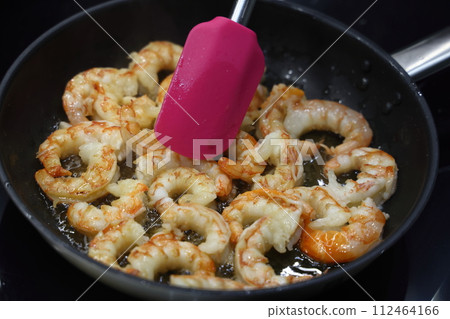 Large shrimp fried in oil in a black frying pan. Freshly fried shrimp in a pan. Large shrimp fried in oil in a black frying pan. Freshly fried shrimp in a pan. 112464166