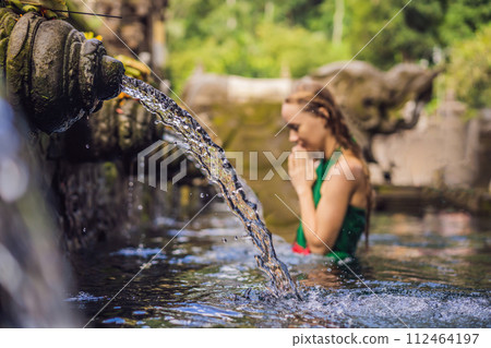 Woman in holy spring water temple in bali. The temple compound consists of a petirtaan or bathing structure, famous for its holy spring water Woman in holy spring water temple in bali. The temple compound consists of a petirtaan or bathing structure, famous for its holy spring water 112464197